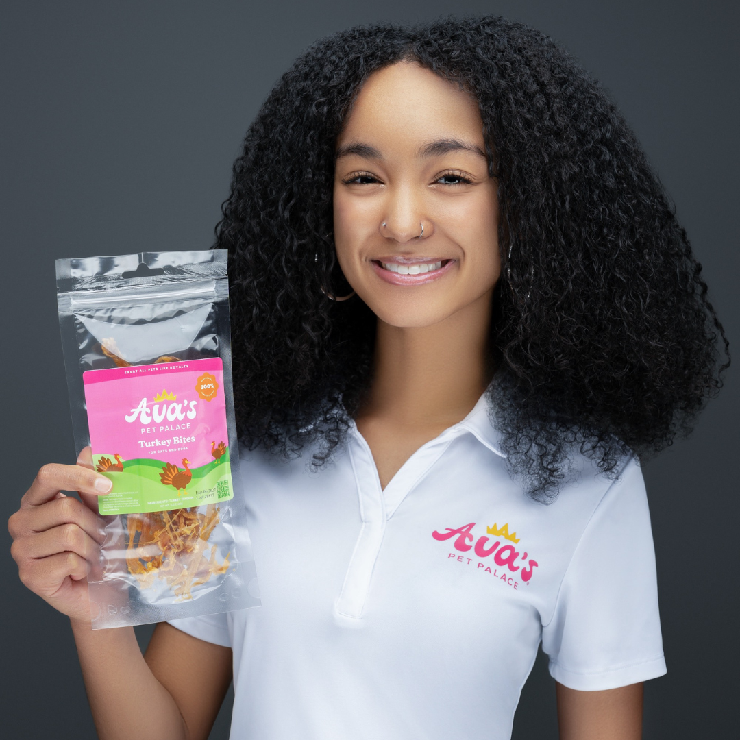 Ava holding a package of Ava's Pet Palace pet food against a dark background